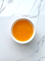 Top view of orange juice squeezed from fresh oranges in a white glass placed on a freshly scented marble background.
