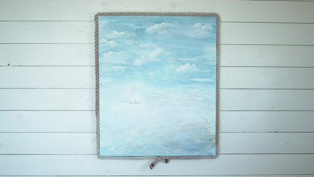 Acrylic painting of a sailing boat at sea hanging on a wooden wall in a seaside cabana.