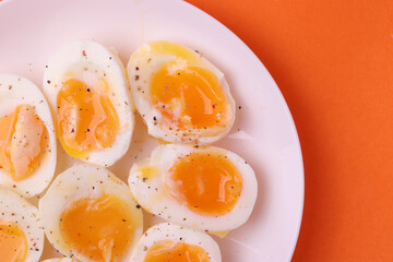 soft-boiled sunny side up halves of chicken eggs on the white plate bright orange background. close up shot. minimalism concept