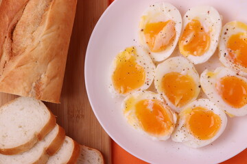 soft-boiled sunny side up halves of chicken eggs on the white plate bright orange background. close up shot. minimalism concept