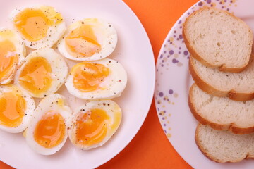 soft-boiled sunny side up halves of chicken eggs on the white plate bright orange background. close up shot. minimalism concept