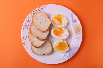 soft-boiled sunny side up halves of chicken eggs on the white plate bright orange background. close up shot. minimalism concept