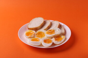 soft-boiled sunny side up halves of chicken eggs on the white plate bright orange background. close up shot. minimalism concept