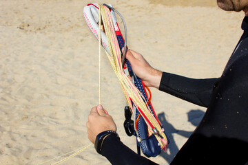 close up a man hands rolling a kite bar and lines on the beach after kitesurfing. Kitesurfing equipment for kite courses. Extreme watersports. Wild lovers. Kiterebels. Space for text