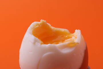 soft-boiled sunny side up halves of chicken eggs on the white plate bright orange background. close...