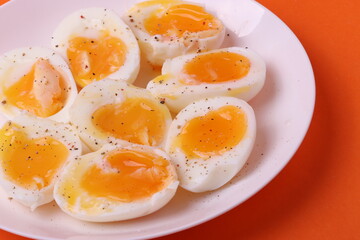 soft-boiled sunny side up halves of chicken eggs on the white plate bright orange background. close up shot. minimalism concept
