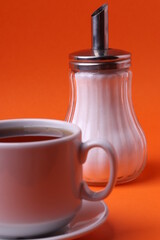 tea cup and a sugar pot bottle on orange