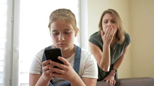 Mom is outraged that she reads a teenage daughter on a mobile phone. Girl hides the phone. Problem of the relationship between parents and children.