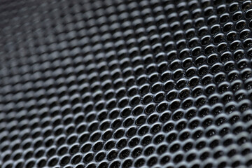 Macro shot of a black metal surface with round holes.