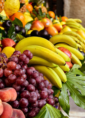 Naklejka na ściany i meble Supply of assorted fresh fruits (bananas, black grapes, flat peaches, ...) displayed for sale