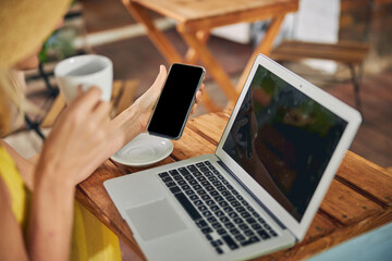 Woman with a cup and a gadget in her hands