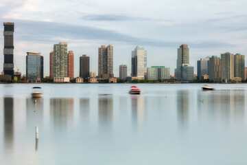 View on Jersey city from Hudson River with boats on the water in long exposure