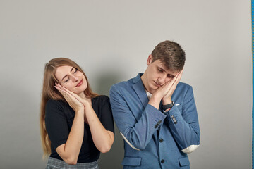 Sleeping with head laid on clasped hands as sweet dreams, eyes closed, close-up, gesturing asleep sign, resting. Young attractive couple boyfriend girlfriend two people, dressed black t-shirt