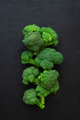 Healthy green organic raw broccoli florets on black background