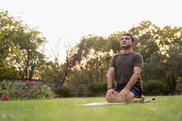 Naklejka na ściany i meble Mid-aged Man doing yoga in a park covered with trees on International Yoga Day.
