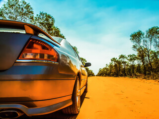 A cinematic photo of a fast shiny silver car on a dusty outback road in Australia. © Archy