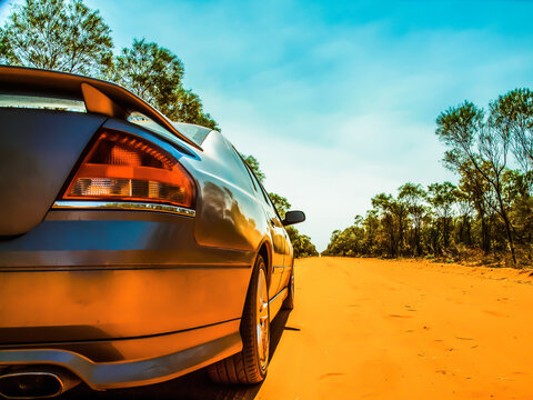 A cinematic photo of a fast shiny silver car on a dusty outback road in Australia.