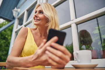 Smiling female with a gadget looking away