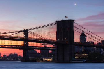 Brooklyn and Manhattan Bridge from East River with a crescent moonrise