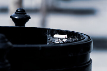 Single cigarette stub in outdoor ashtray closeup