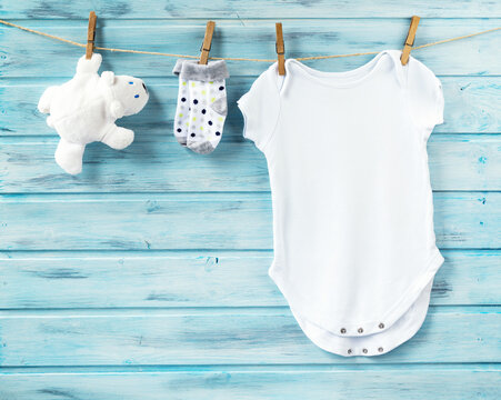 Baby boy white clothes and bear toy with socks on a clothesline, blue wooden background