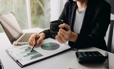 womman using laptop and typing and holding coffee cup in cafe, home office in morning light