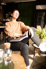Girl blogger with a cup of coffee in cafe with magazine