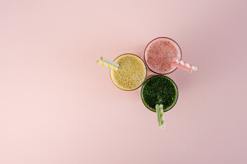 Flat Lay of Three Different Colored Smoothie Cocktails on Pink Background