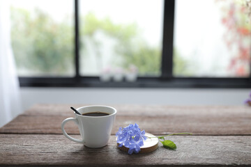 White coffee cup with blue plumbago flower on rustic wooden dinning table interior home
