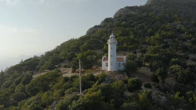 Gelidonya lighthouse on a background of mountains. Beautiful ladscape with dense forest. Drone footage 4K