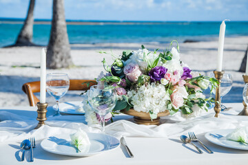 Table setting served and decorated for party event with plates, glasses, candles, napkins, lamps, flowers and invitations. Guests table, Wedding reception, Birthday, anniversary. Holiday evening