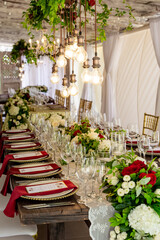 Table setting served and decorated for party event with plates, glasses, candles, napkins, lamps, flowers and invitations. Guests table, Wedding reception, Birthday, anniversary. Holiday evening