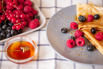 Two homemade pancakes with honey and fresh ripe raspberries and blackberries
