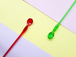 colorful plastic spoons on yellow pink paper background. 