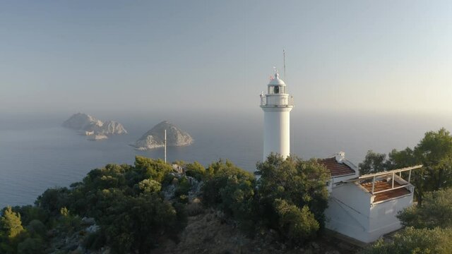 An old white lighthouse facing the Greek islands. Drone footage 4K.