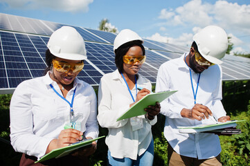 African american technician checks the maintenance of the solar panels. Group of three black engineers meeting at solar station.