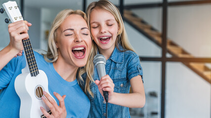 Caucasian mother with little girl singing in karaoke at home