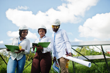 African american technician checks the maintenance of the solar panels. Group of three black engineers meeting at solar station.