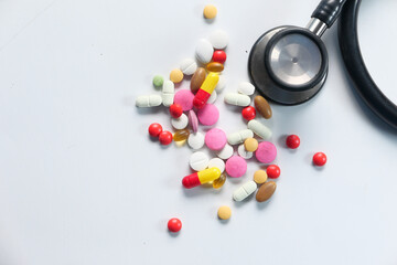 colorful pills spilling and stethoscope on white background 