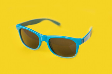 Blue summer sunglasses Isolated on a yellow background. Summer sun accessories