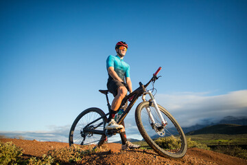 Naklejka na ściany i meble Close up portrait of a mountain biker on his mountain bike on a bike track