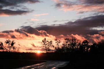 Sunset clouds after the rain over field with puddles