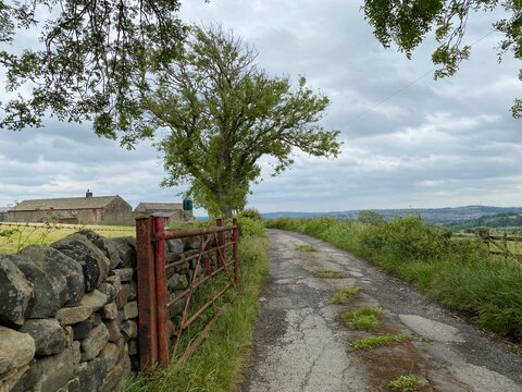 Open farm, gate, with a track leading to a farm in, Hawksworth, Leeds, UK