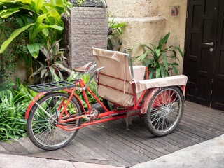 Fototapeta na wymiar Red housekeeping tricycle cart in front of the resort door.