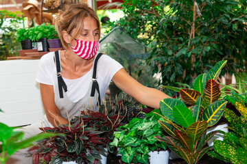 woman with mask works in a plant nursery