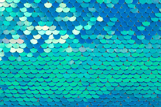 Abstract textured holographic background from turquoise shiny iridescent sequins, like mermaid or fish scales. Trendy texture with copy space. Celebration, holidays, fashion concept. Horizontal