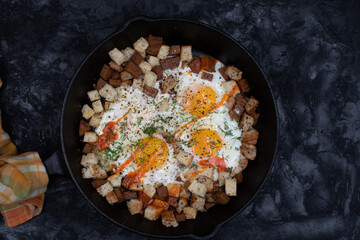 Fried eggs with seitan and bread, herbs, in cast iron pan