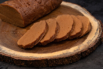 Sliced seitan on wooden board on dark table