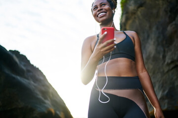 Cheerful excited female jogger dressed in stylish tracksuit feeling good from spending time for...