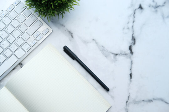 office desk with keyboard and notepad on white desk top down 
